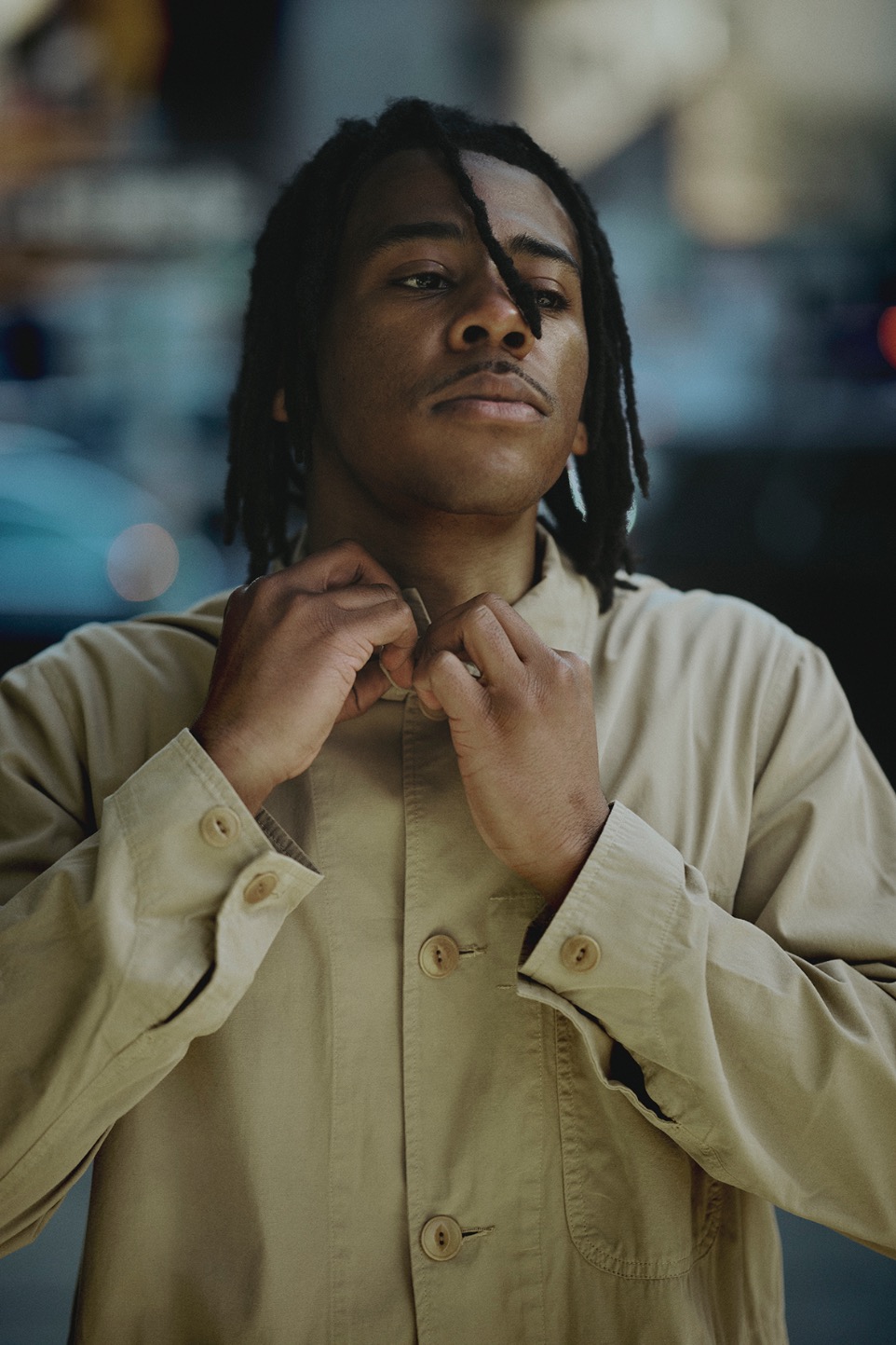 man butonning his khaki jacket