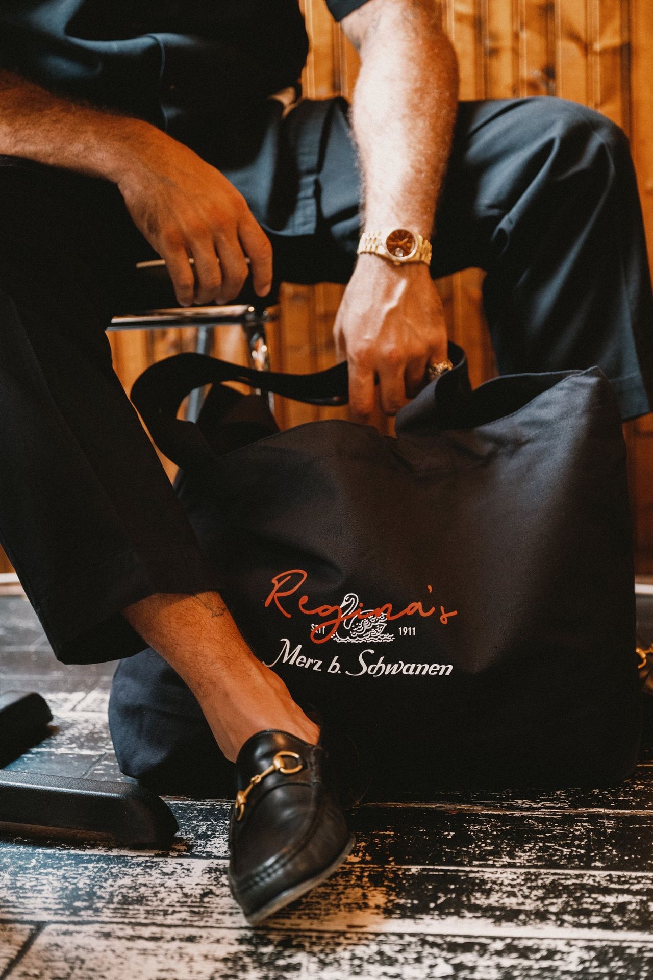 Man on a chair holding black tote bag