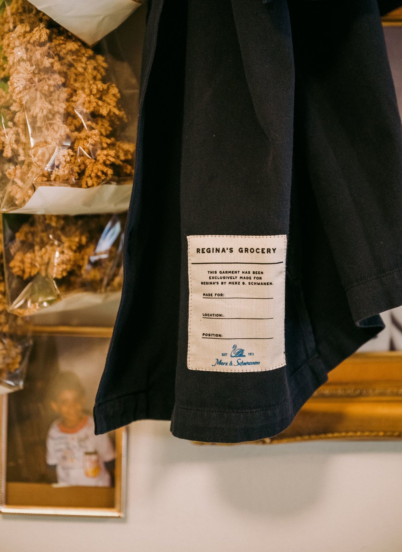 Black worker shirt with woven label hanging in front of a mirror