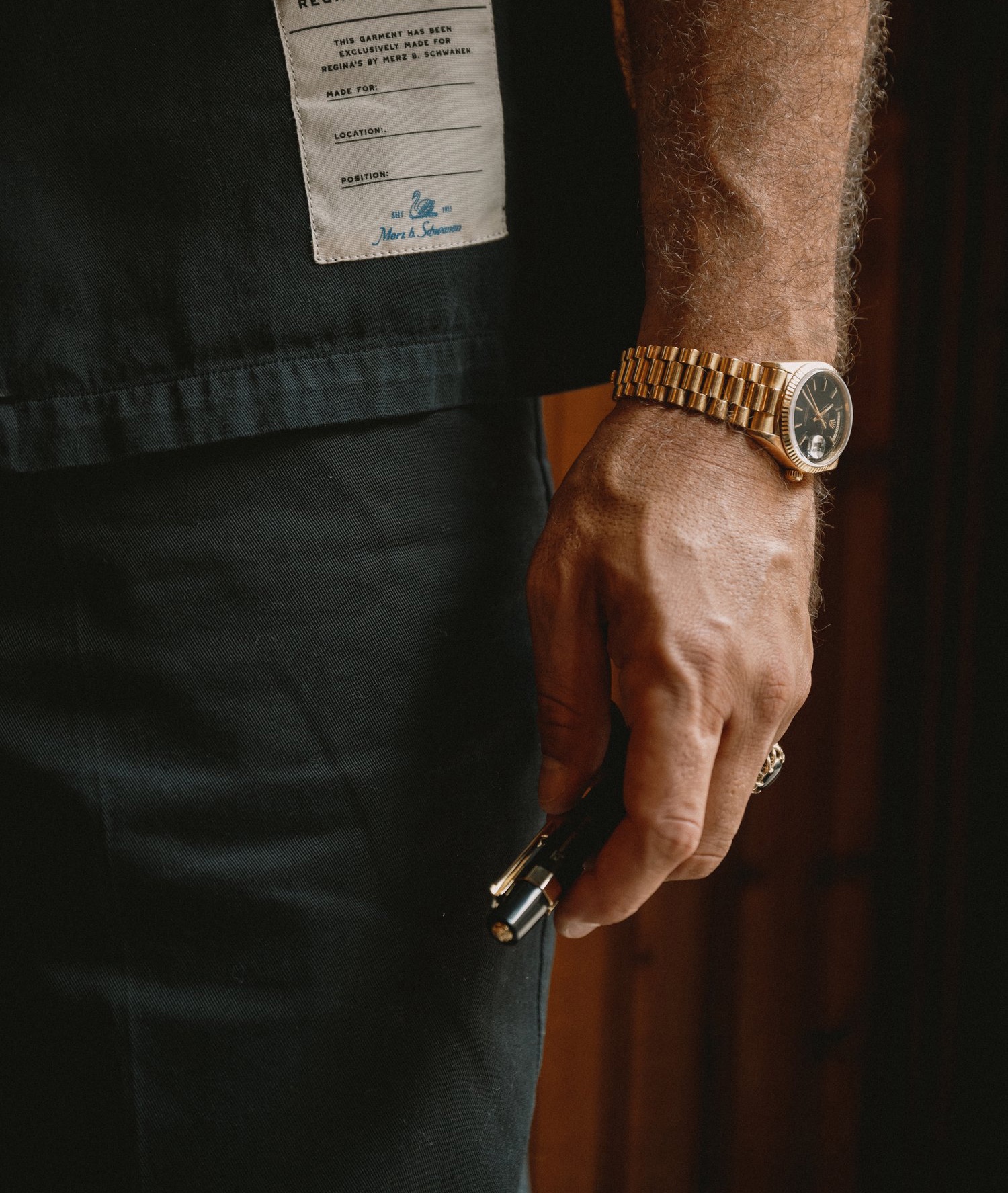 Man in black worker shirt and chino trousers holding a metal pencil