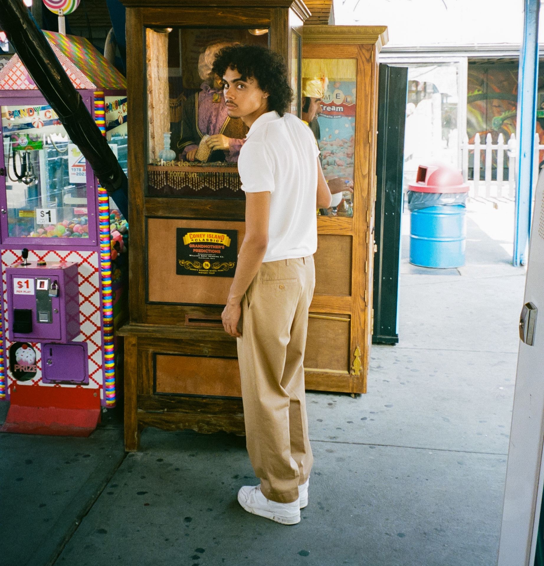 Man in white polo shirt and khaki chino trousers in front of vending machine